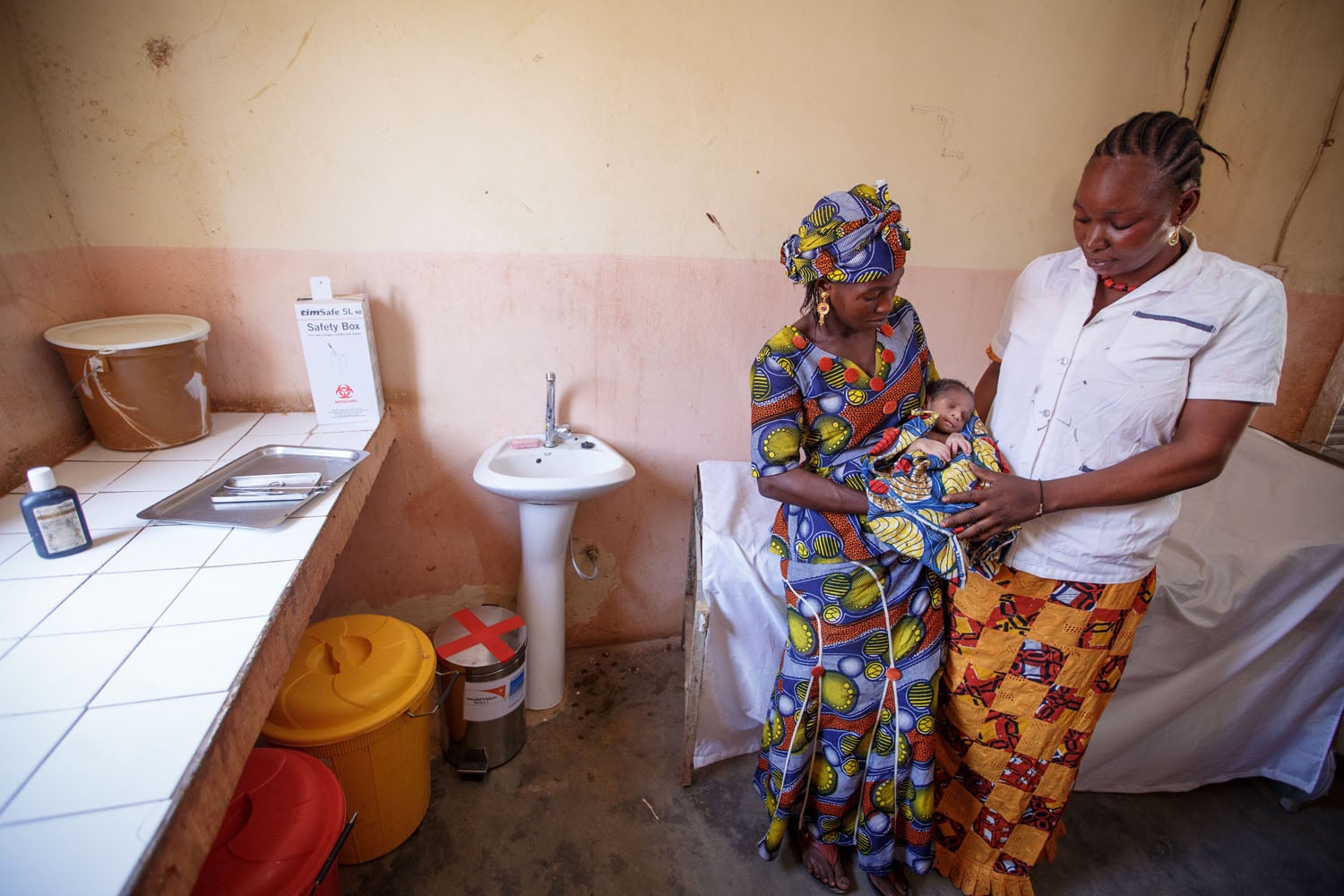 Nurse examining baby with mother in HCF